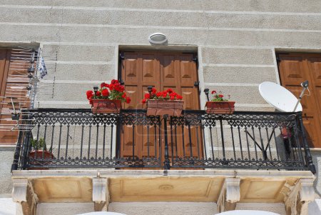 Typisch griechischer Balkon mit Antenne, Blumen und Satellitenschüssel in Samos, Griechenland