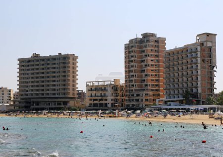 Téléchargez les photos : VAROSHA, FAMAGUSTA, CHYPRE-NORD-AOÛT 30 2023 : Des personnes non identifiées profitent d'une journée à la plage par les hôtels abandonnés - en image libre de droit