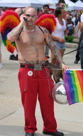 Téléchargez les photos : INDIANAPOLIS, IN, États-Unis-13 JUIN 2009 : Homme non identifié avec des ailes d'ange colorées et des tatouages tenant un bal disco et un drapeau de fierté à Indy Pride - en image libre de droit