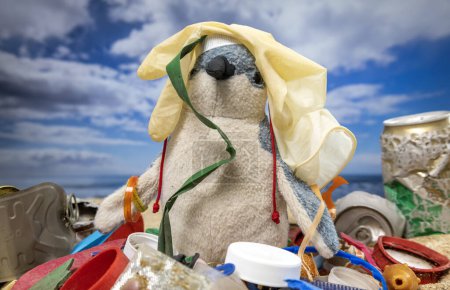 Foto de Un peluche de pingüinos rodeado de basura y basura en una hermosa playa - Imagen libre de derechos