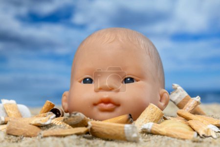 Photo for A baby doll surrounded by cigarettes on a beautiful beach - Royalty Free Image