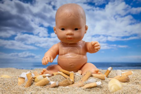 Foto de Una muñeca rodeada de cigarrillos en una hermosa playa - Imagen libre de derechos
