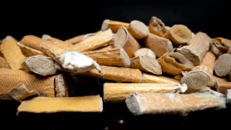 Photo for Cigarettes butts pile on black background - Royalty Free Image