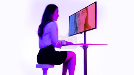 Téléchargez les photos : Une femme d'affaires tapant le code sur un ordinateur avec son propre visage à l'écran pour le balayage du visage - en image libre de droit