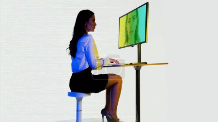 Photo for A businesswoman typing code on a computer with her own face on screen for face scan - Royalty Free Image