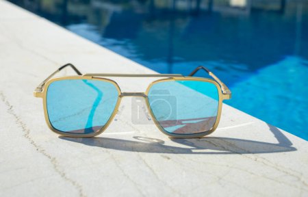 Photo for Mirrored sunglassesnext to a pool - Royalty Free Image
