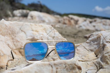 Foto de Gafas de sol espejadas en una playa que refleja el mar - Imagen libre de derechos