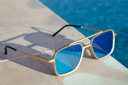 Photo for Mirrored sunglassesnext to a pool - Royalty Free Image
