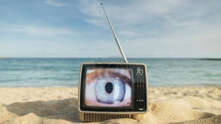 Photo for Retro televisions with beautiful female eye on the screen next to the sea - Royalty Free Image