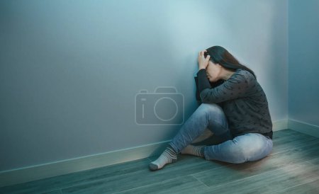 Téléchargez les photos : Femme méconnaissable avec trouble anxieux avec les mains dans la tête assise sur le sol - en image libre de droit