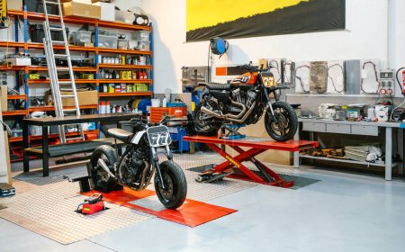 Foto de Taller de motocicletas vacío con motos personalizadas sobre plataformas listas para reparar. Dos motocicletas scrambler en revisión en garaje mecánico limpio. Espacio de copia derecha. - Imagen libre de derechos