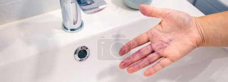 Foto de Primer plano de la mujer irreconocible quitando purpurina brillo de su mano en el lavabo en el baño. Contaminación del agua por concepto de composición de microplásticos. - Imagen libre de derechos