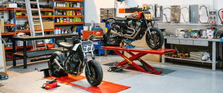 Foto de Banner de taller de motocicletas vacío con motos personalizadas sobre plataformas listas para reparar. Dos motocicletas scrambler en revisión en garaje mecánico limpio. Espacio de copia derecha. - Imagen libre de derechos