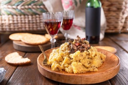 Photo for Creamy polenta with porcini mushrooms, bacon, served on a dark wooden background with a glass of red wine. Typical food of northern Italy, Trentino in the Alps - Royalty Free Image