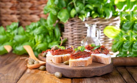 Téléchargez les photos : Bruschetta with sun-dried tomatoes, cheese, basil and capers. Traditional appetizer for aperitivo in Italy. High quality photo. Copy space. High quality photo - en image libre de droit