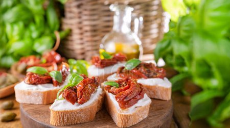 Téléchargez les photos : Bruschetta with sun-dried tomatoes, cheese, basil and capers. Traditional appetizer for aperitivo in Italy. High quality photo. Copy space. High quality photo - en image libre de droit