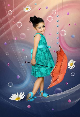 Téléchargez les photos : Petite fille avec un sourire sur le visage dans une belle robe et avec un parapluie à la main sur un fond bleu rose - en image libre de droit