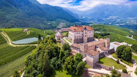 Foto de Castillos medievales hermosos del norte de Italia - espléndido castillo de Thun entre los manzanos de Val di Non. Región de Trentino, provincia de Trento. Vista panorámica del dron aéreo - Imagen libre de derechos