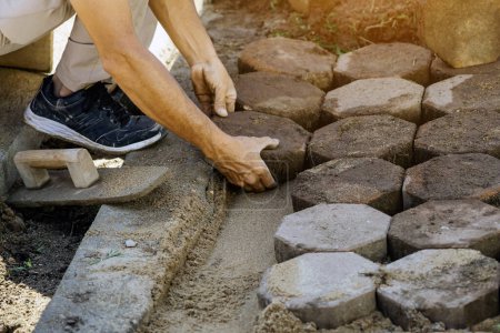 Photo for Hands of workman make it fit and to place stone pavers in a row. Construction site of pavement octagon bricks road. Installation or renovation repair. Lays out paving slabs. Selective focus on hands. - Royalty Free Image
