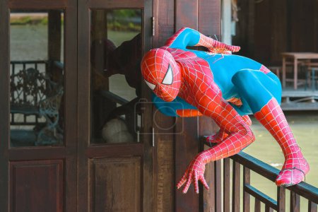 Foto de RAYONG-TAILANDIA, 13 de agosto de 2023: Una hermosa estatua de la decoración de modelo de figura de Spiderman en el balcón de madera de la cerca en el mercado flotante de Ko Kloi. Un personaje de cómic cosplay. Spider-Man traje de maravilla. - Imagen libre de derechos