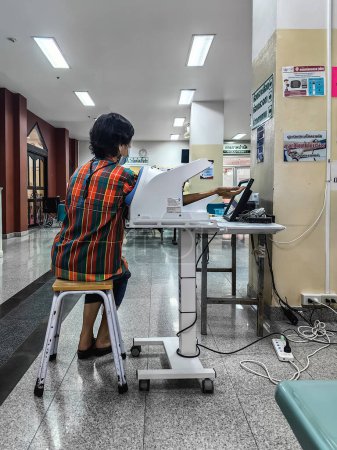Foto de KANCHANABURI, TAILANDIA-FEBRERO 7,2024: Mujer mayor asiática no identificada comprueba la presión arterial y el ritmo cardíaco con una máquina automática de presión arterial digital en el Hospital Somdet Phra Sangharaja 19. - Imagen libre de derechos