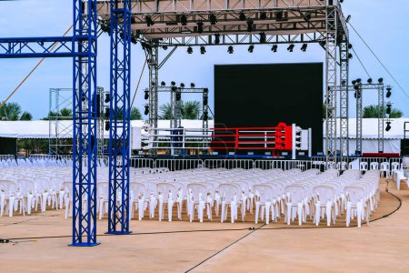 Boxing ring and many chairs for spectators prepared for competition, Outdoors. Sport and empty boxing ring in the city for a wrestling competition for athletes or boxers. Boxing ring with white seats.