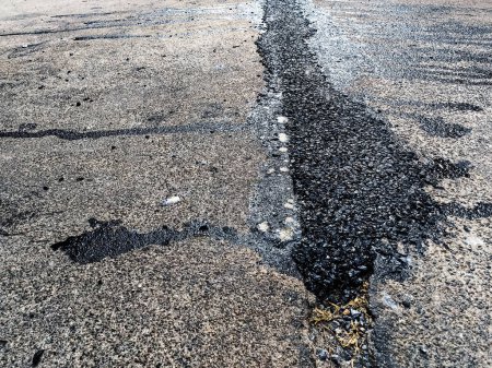 Asphalt on road. Street with black tar filling the cracks. Cracks in concrete surface are then filled with asphalt. Texture of old asphalt road. Asphalt is covered with cracks, which filled with tar.