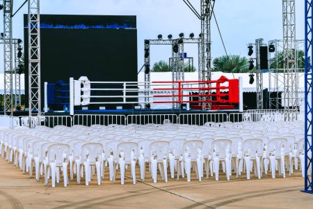 Boxing ring and many chairs for spectators prepared for competition, Outdoors. Sport and empty boxing ring in the city for a wrestling competition for athletes or boxers. Boxing ring with white seats.