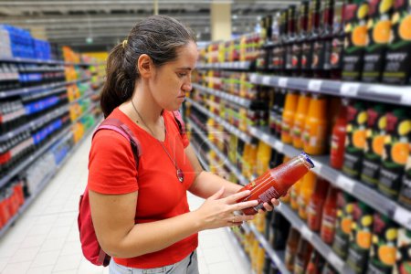 A female customer is interested in juice in grocery store, supermarket