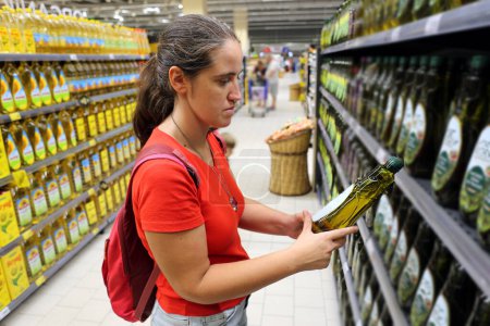 A female customer is interested in olive oil in grocery store, supermarket