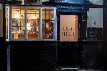 Foto de Sawbridgeworth, Hertfordshire / Inglaterra 13 de septiembre de 2022: El pub Old Bell en la calle Bell en Sawbridgeworth, una vista nocturna a través de la ventana frontal del propietario que sirve - Imagen libre de derechos