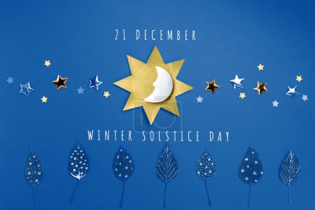 Foto de Fiesta del solsticio de invierno, 21 de diciembre. El concepto de la noche más larga del año. Sol, luna, estrellas doradas y símbolo del bosque de invierno sobre fondo azul. Plano, vista superior, espacio para copiar - Imagen libre de derechos