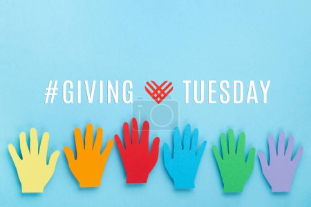 Giving Tuesday, global day of charitable giving after Black Friday shopping day. Charity, give help, donations support concept. Colorful hands and red heart on blue background, copy space, top view.