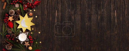 Téléchargez les photos : Solstice d'hiver, 21 décembre. La plus longue nuit de l'année. Symbole soleil et lune, sapins de Noël, cônes de pin, branches de paddub aux baies rouges, bougie sur fond bois foncé, vue sur le dessus. - en image libre de droit