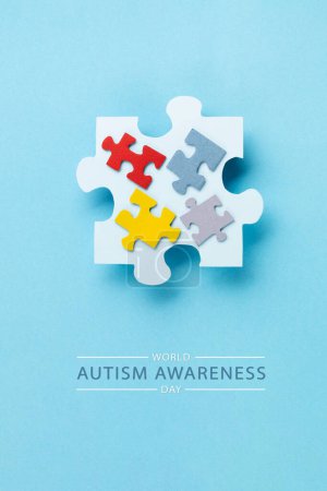 Foto de World Autism Awareness Day or month concept (en inglés). Diseño creativo para el 2 de abril. Rompecabezas de color, símbolo de conciencia para el trastorno del espectro autista sobre fondo azul. Vista superior, espacio de copia. - Imagen libre de derechos
