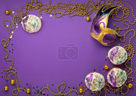 Téléchargez les photos : Mardi Gras King Cake sufganiyot beignets, mascarade festival carnaval masque, perles d'or et d'or, vert, confettis violets sur fond violet. Invitation de fête, concept de carte de vœux. Vue du dessus - en image libre de droit