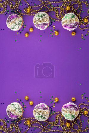 Photo for Mardi Gras King Cake sufganiyot donuts, masquerade festival carnival gold beads and golden, green, purple confetti on purple background. Holiday party invitation, greeting card concept. - Royalty Free Image