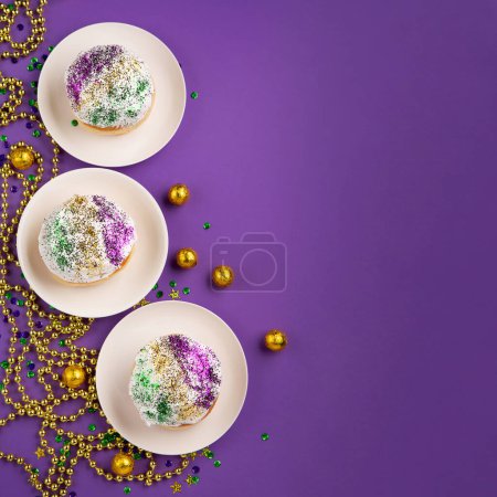 Mardi Gras King Cake Sufganiyot Donuts, Maskerade Festival Karneval Goldperlen und goldenen, grünen, lila Konfetti auf violettem Hintergrund. Feiertagseinladung, Grußkarten-Konzept.