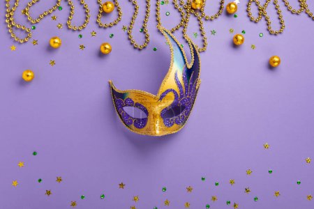 Photo for Mardi Gras King Cake masquerade festival carnival mask, gold beads and golden, green confetti on purple background. Holiday party invitation, greeting card concept. - Royalty Free Image