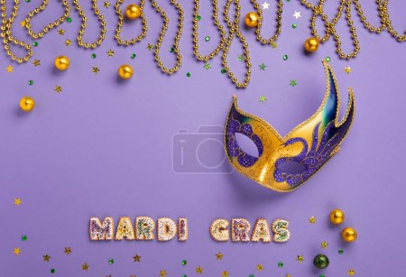Foto de Mardi Gras King Cake cookies, masquerade festival carnival mask, gold beads and golden, green confetti on purple background. Holiday party invitation, greeting card concept. - Imagen libre de derechos
