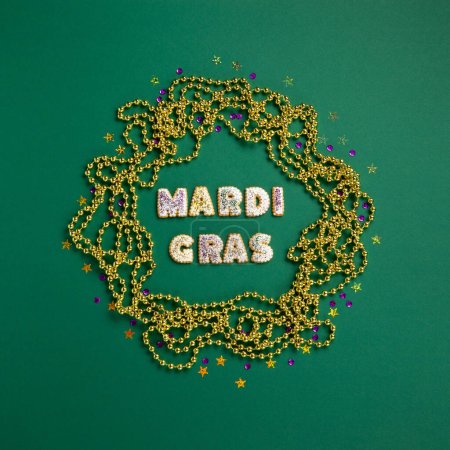 Photo for Mardi Gras King Cake ccookies, masquerade festival carnival mask, gold beads and golden, green, purple confetti on green background. Holiday party invitation, greeting card concept. - Royalty Free Image