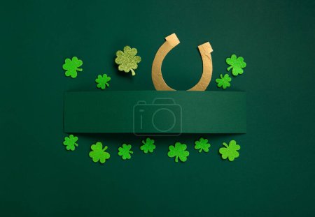 Foto de St. Patrick's Day celebration Concept. Greeting card with traditional symbols - Golden horseshoe, gold coins and clover leaves, green shamrocks on green background. Top view, copy space. - Imagen libre de derechos