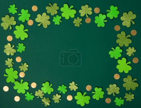Foto de St. Patrick's Day celebration Concept. Greeting card with traditional symbols - Golden horseshoe, gold coins and clover leaves, green shamrocks on green background. Top view, copy space. - Imagen libre de derechos