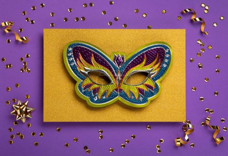 Mardi Gras masquerade festival carnival mask, gold beads and golden, green confetti on purple background. Holiday party invitation, greeting card concept.