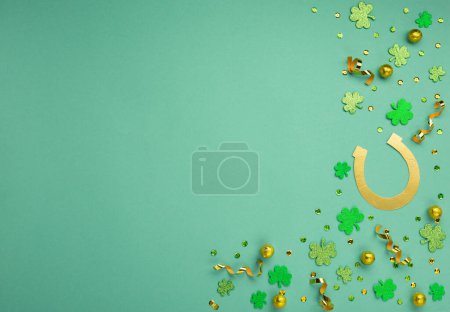 Foto de St. Patrick's Day celebration Concept. Greeting card with traditional symbols - Golden horseshoe, gold coins and clover leaves, green shamrocks on green mint background. Top view, copy space. - Imagen libre de derechos