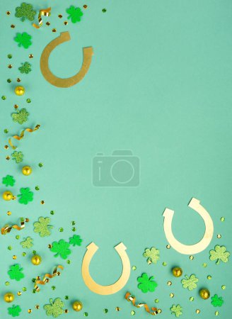 Téléchargez les photos : St. Patrick's Day celebration Concept. Greeting card with traditional symbols - Golden horseshoes, gold coins and clover leaves, green shamrocks on green mint background. Top view, copy space. - en image libre de droit