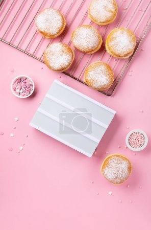 Téléchargez les photos : Happy National donut day or Valentines Day Concept. Donuts doughnuts with icing sugar and sugar sprinkles on pink background, copy space. Colorful carnival or birthday party card. - en image libre de droit