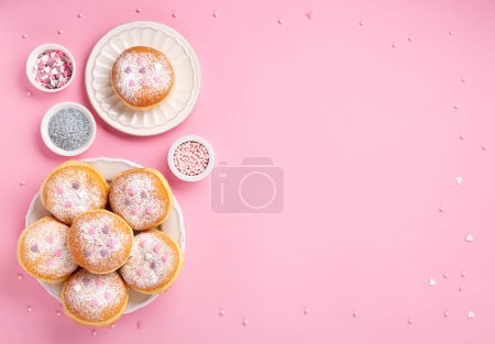 Téléchargez les photos : Happy National donut day or Valentines Day Concept. Donuts doughnuts with icing sugar and sugar sprinkles on pink background, copy space. Colorful carnival or birthday party card. - en image libre de droit