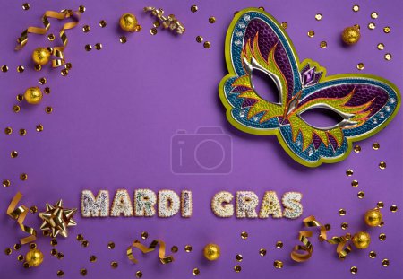 Photo for Mardi Gras masquerade festival carnival Mask, chocolate candies in foil, gold beads and golden confetti on purple background. Holiday party invitation, greeting card concept. - Royalty Free Image