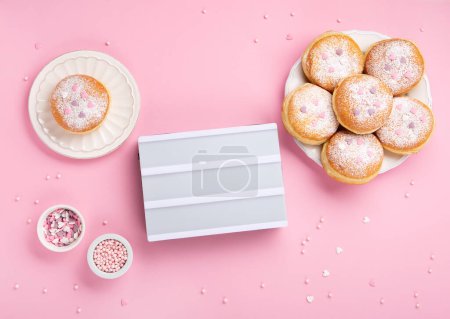 Foto de Happy National donut day or Valentines Day Concept. Donuts doughnuts with icing sugar and sugar sprinkles on pink background, copy space. Colorful carnival or birthday party card. - Imagen libre de derechos